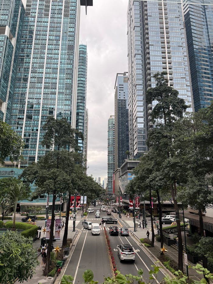 about-01 View of Makati Avenue showcasing towering skyscrapers and lush greenery, bustling with traffic.